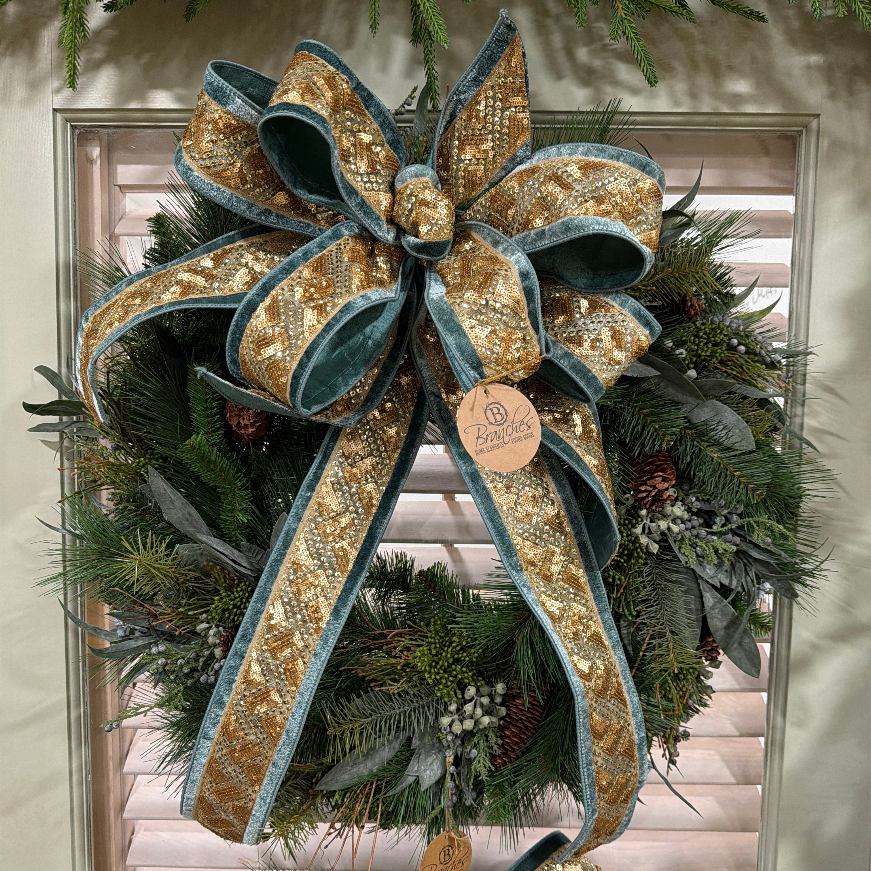 Decorative wreath with gold and teal blue ribbons on a door