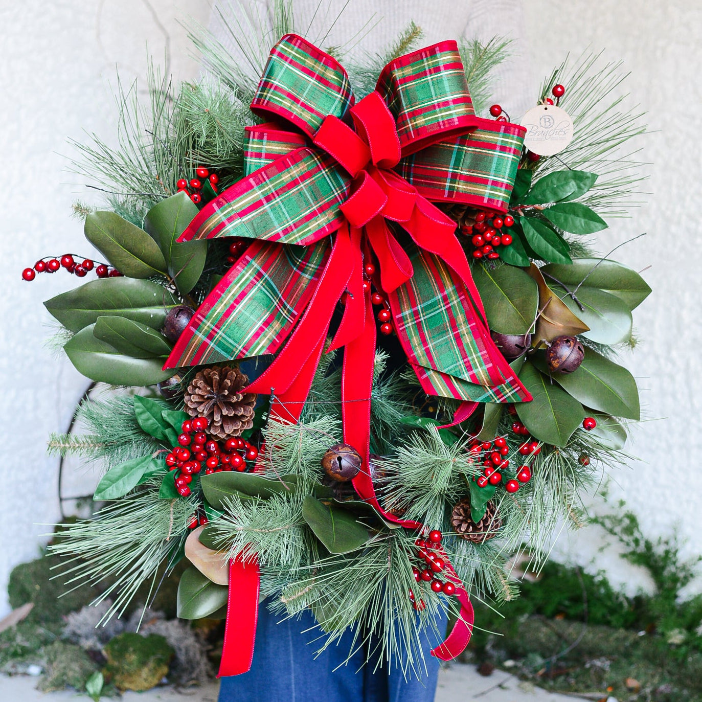Woman holding a large Christmas wreath with a plaid bow against a white background hilton head island south carolina