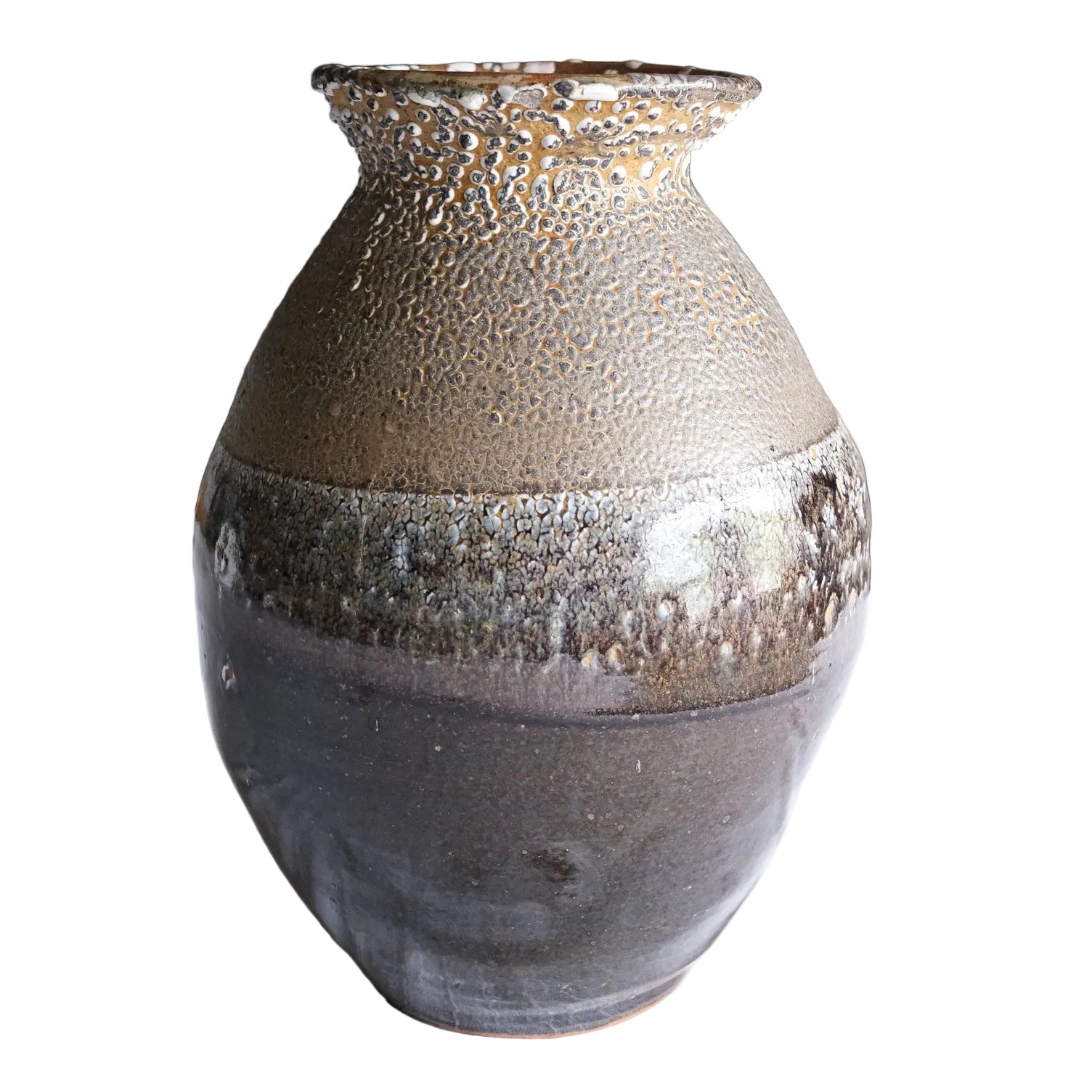 Textured ceramic vase on a white surface with a blurred indoor background