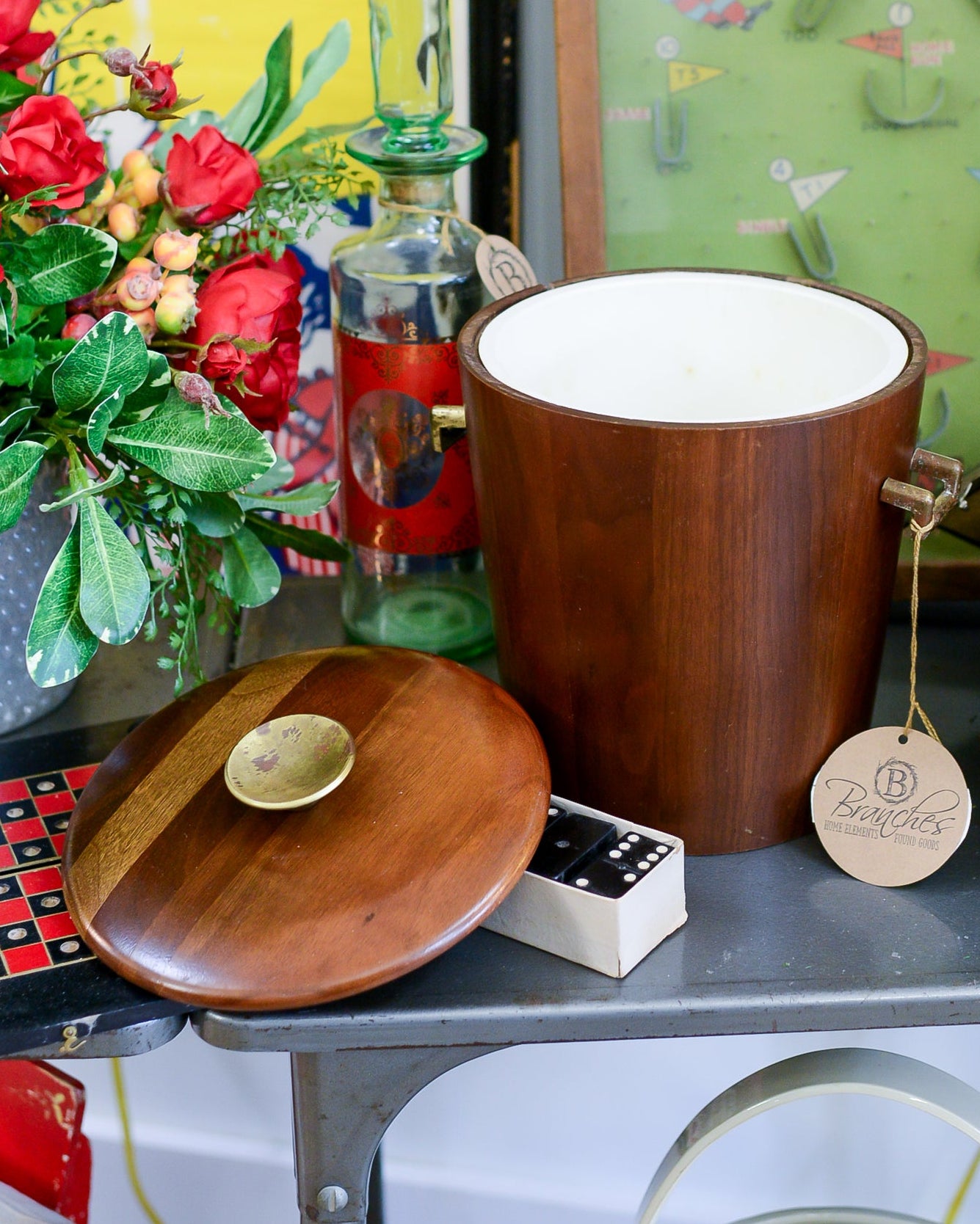Wooden ice bucket with a wooden lid on a table with decorative items.